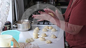 Weathered hands carefully prepare small dough balls on a wooden surface. The scene offers a counterpoint to fast food