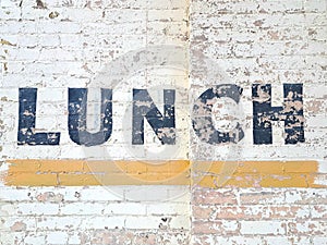 Weathered Painted Sign Saying Lunch in Black Block Letters on a Brick Wall of an Old American Diner