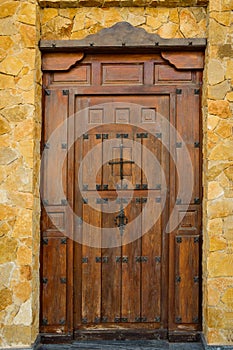 Weathered Plank Wood entrance door of residential house mansion villa with wrought-iron hinges latches. Dark brown earthy color