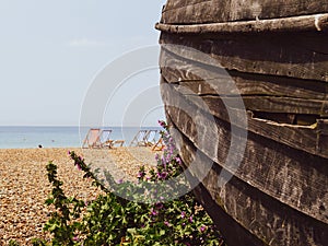 Weathered planks of old wooden boat rotting away in foreground on Brighton Beach