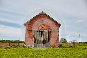 Weathered Red Brick Barn in Rural Landscape with Blue Sky