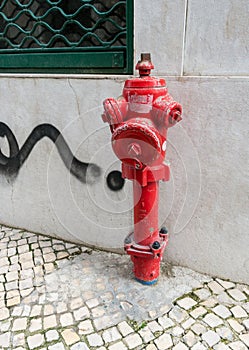 Weathered red fire hydrant near a cement wall