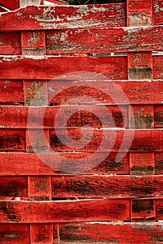 Weathered red painted woven wood fence slats pattern background texture