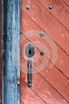 Weathered red wood door with old iron lock and handle