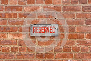 Weathered reserved sign on brick wall