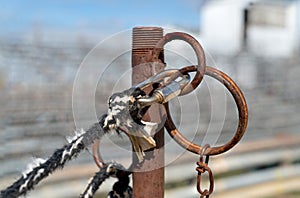 Weathered rope with clevis attached to a rusty steel pipe hitching post