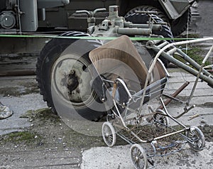 Weathered rusty vintage baby pram and military vehicle on courtyard