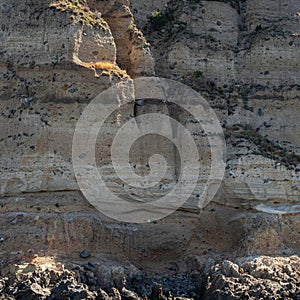 Weathered seaside rock face texture. Aged volcanic stone wall surface background