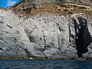 Weathered seaside rock face texture. Aged volcanic stone wall surface background pattern