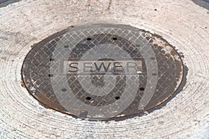 Weathered sewer manhole cover on a road