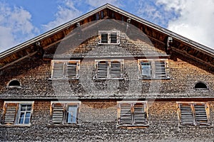 Weathered shingle house facade with window shutters photo