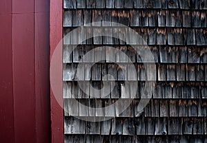 Weathered shingles of an old mill building against a red wood wall