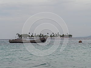 Weathered small boat with island in the background on an overcast day at Kuna Yala Panama photo