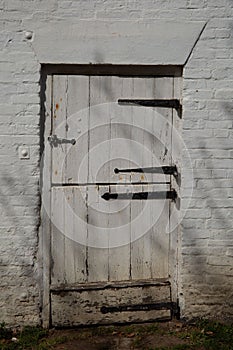 Weathered stable white door in an old brick wall, vertical