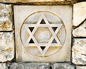 Weathered star of david in rock wall photo