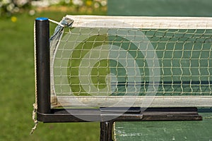 Weathered table tennis net stretched on old green tennis table