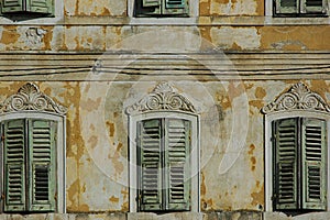 Weathered window shutters of an abandoned house, with ornate details and chipped paint