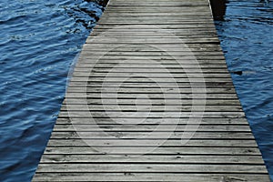 Weathered wood dock leading across the lake - passing stormy waters