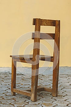 Weathered wooden chair in front of yellow wall