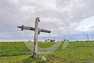 Weathered Wooden Cross Marking the Memory of a Loved one in a Green Field