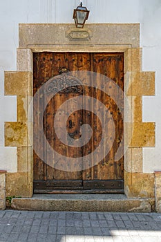 Weathered wooden door in stone wall of residential house in historic walled Vila Vella Old town in Tossa de Mar