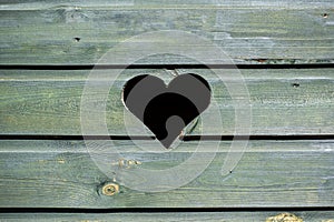 Weathered wooden green fence with heart shaped peephole