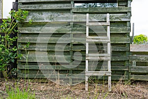 Weathered wooden ladder leaning on wooden slats