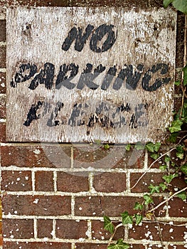 Weathered wooden parking sign on brick wall