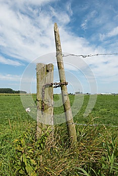 Weathered wooden post with barbed wire against a blue sky