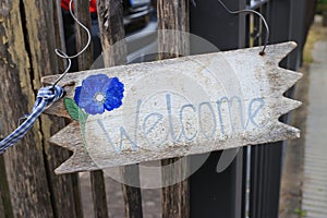 Weathered wooden welcome sign hanging on a fence