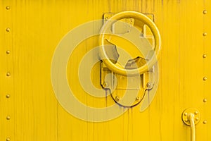 Weathered yellow painted metal background with valve wheel