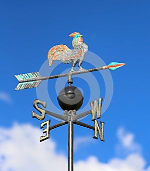 weathervane with rooster above an arrow and the four cardinal p