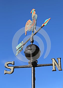 weathervane with rooster above an arrow and the four cardinal p