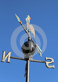 weathervane with rooster above an arrow and the four cardinal p