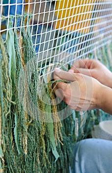 Weaving a camouflage uniform for a sniper.Ukrainian volunteer girl weaves the basics for a camouflage coat for a soldier