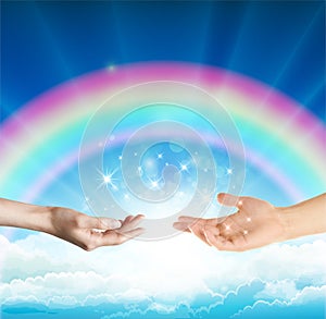 Magical love healing energy from hands with rainbow sky background