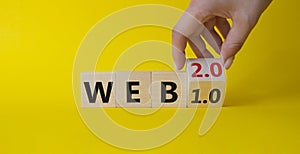 WEB 2 or 1 symbol. Businessman hand Turnes cube and changes word WEB 1.0 to WEB 2.0. Beautiful yellow background. Business and WEB