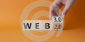 Web 3.0 vs Web 2.0 symbol. Hand turns cubes and changes the word web 2.0 to web 3.0. Beautiful orange background. Businessman hand