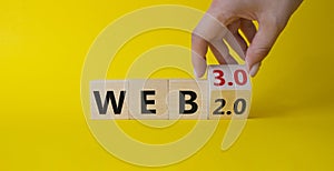 Web 3.0 vs Web 2.0 symbol. Hand turns cubes and changes the word web 2.0 to web 3.0. Beautiful yellow background. Businessman hand