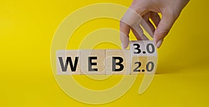 Web 3.0 vs Web 2.0 symbol. Hand turns cubes and changes the word web 2.0 to web 3.0. Beautiful yellow background. Businessman hand