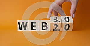 Web 3.0 vs Web 2.0 symbol. Hand turns cubes and changes the word web 3.0 to web 2.0. Beautiful orange background. Businessman hand