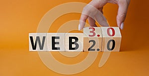 Web 3.0 vs Web 2.0 symbol. Hand turns cubes and changes the word web 3.0 to web 2.0. Beautiful orange background. Businessman hand