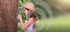Web banner of children& x27;s education and curiosity. Smiling little girl in a straw hat looks at the tree bark through