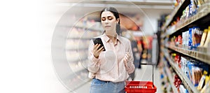 Web banner of shopping with mock up. Young Caucasian woman uses smartphone and holds basket in her hands. Concept of