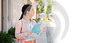 Web banner of travel. Portrait of young Caucasian woman holding paper map and looking for way. Mock up. Sunny street in