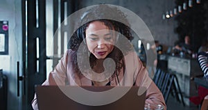 Web conference concept. Young beautiful happy mixed race female freelancer with curly hair using laptop webcam at work.