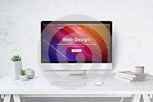 Web design studio concept with computer on work desk and company web site on display