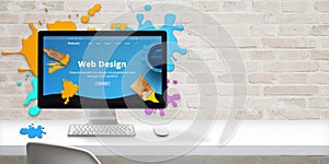 Web design studio concept with modern web site teme and web design text on computer display surrounded by color drops