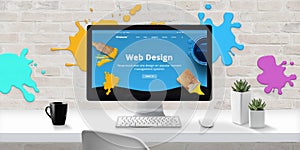 Web design studio with modern web site theme on computer display with color drops on brick wall