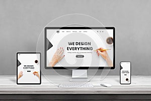 Web design studio with multiple devices on office desk. Concept of responsive, flat web page design photo